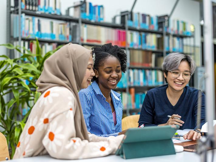 Three young multiracial female scholars in library