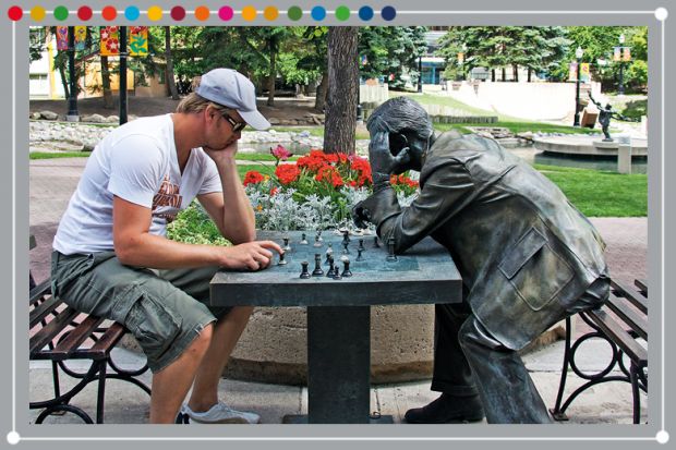 Person playing chess against a statue, illustrating the need to value technical knowledge and soft skills